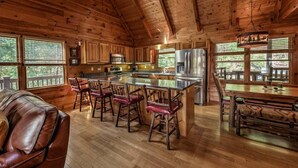 A cabin interior with a wooden interior, a kitchen with a large island, and a dining area.