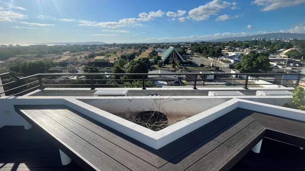 A rooftop terrace with a view of a town, including a distinctive building with a green roof.