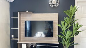 A modern entertainment unit with a flat-screen TV, wooden shelves, and a decorative clock on the wall.
