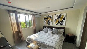 A modern bedroom with a large bed, a nightstand, a chair, and artwork on the walls.