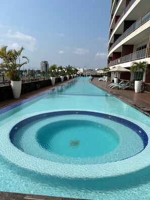 Relax by the pool surrounded by lush greenery and lounge chairs.