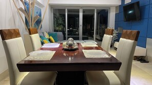 Enjoy meals in this dining area with a table for four, a flat-screen TV, and a sliding glass door leading to an outdoor space.