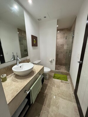 Features a large vessel sink, compact toilet, and glass-enclosed shower area.