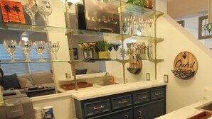 Een moderne keuken met donkere kastjes, een koffieapparaat en een glazen vitrine met diverse spullen.