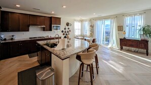 A modern kitchen with a central island, wooden cabinets, and a dining area with a view. - Views, Views, Views.Beautiful 2800 sqft 30 mins to Tahoe large backyard. (Reno)