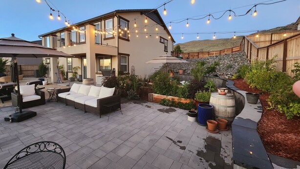 A patio area with outdoor furniture, string lights, and potted plants. - Views, Views, Views.Beautiful 2800 sqft 30 mins to Tahoe large backyard. (Reno)