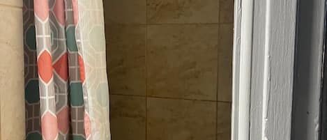 A shower area with a patterned shower curtain and a handheld showerhead.