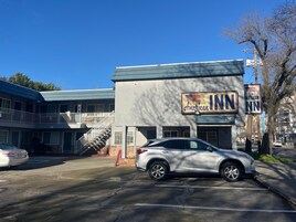 Un edificio con un letrero que dice 'American INN' y un estacionamiento con una camioneta SUV blanca.