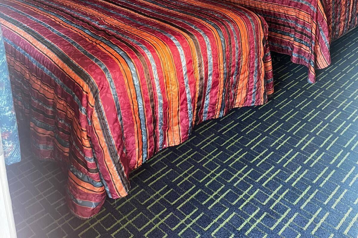 Habitación de hotel con dos camas, una mesita de noche, una lámpara y una puerta.