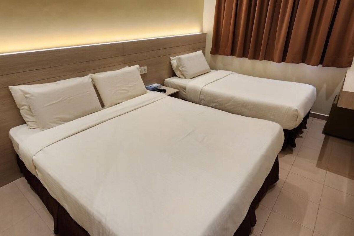 A hotel room with two beds, a wooden headboard, a nightstand, and a curtain.