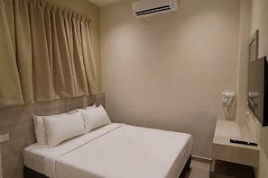 A hotel room with a bed, curtains, an air conditioning unit, a TV, and a charging station. - Eighteen Guesthouse (Kuala Kuantan)