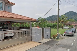 A residential house with a tiled roof, a fenced yard, and parked cars. - Eighteen Guesthouse (Kuala Kuantan)