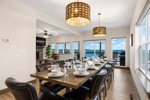 Uma sala de jantar com uma mesa comprida posta para seis pessoas, lareira e vista para o exterior.