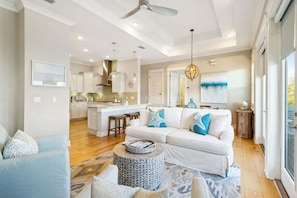 A modern living room with a sofa, coffee table, and a view of the kitchen.