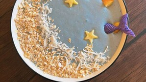 A round table with a blue surface and decorative elements including star-shaped cookies and purple mermaid tails. - Wonderland Hostel (Antigua Guatemala)