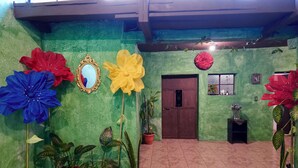 A room with green walls, a tiled floor, and several potted plants. - Wonderland Hostel (Antigua Guatemala)
