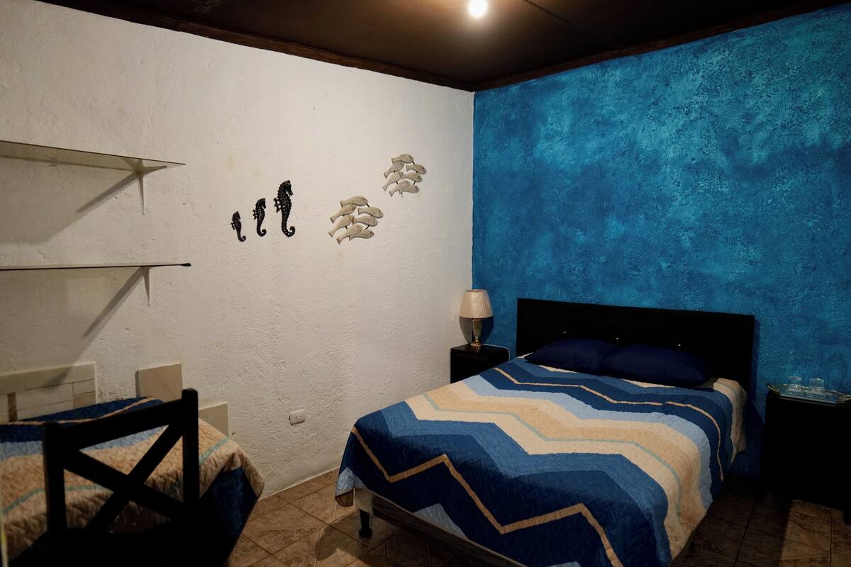 Ein Schlafzimmer mit einem Bett, einem Sessel, einem Nachttisch und einer Wand mit Dekorationen.