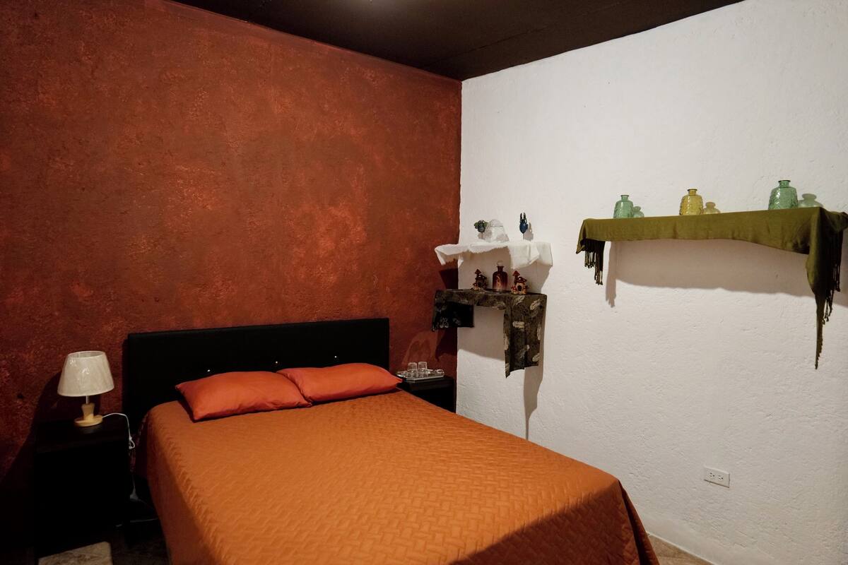 Ein Zimmer mit einem Bett, einem Nachttisch mit Lampe und einem Regal mit Dekorationen.