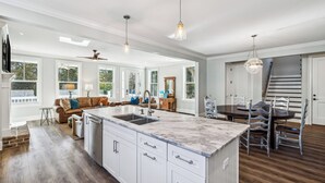 A spacious kitchen with a large island, white cabinetry, and a dining area with a table and chairs. - Experience luxury at 5 Periwinkle Lane, with private pool and a 5-minute walk to the beach! (Hilton Head Island)