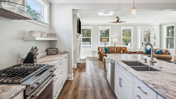 A modern kitchen with a large island, built-in oven, and a dining area with a sofa and table. - Experience luxury at 5 Periwinkle Lane, with private pool and a 5-minute walk to the beach! (Hilton Head Island)