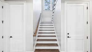 A staircase with white walls and wooden steps leading to a landing. - Experience luxury at 5 Periwinkle Lane, with private pool and a 5-minute walk to the beach! (Hilton Head Island)