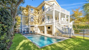 A two-story house with a pool, a covered patio, and a staircase leading to a balcony. - Experience luxury at 5 Periwinkle Lane, with private pool and a 5-minute walk to the beach! (Hilton Head Island)