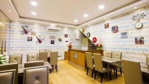 Un restaurante con pared de ladrillos, un mostrador de recepción de madera y varias mesas con sillas.