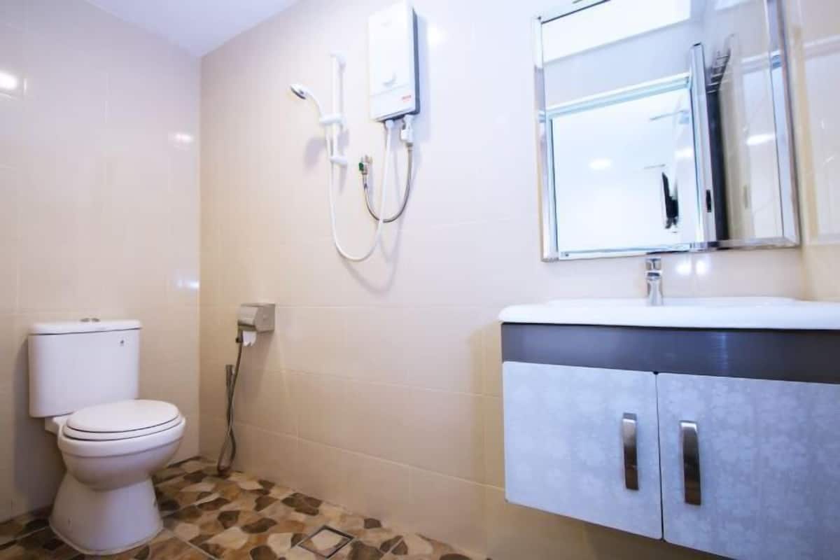 A bathroom with a toilet, a shower, a sink, and a mirror.