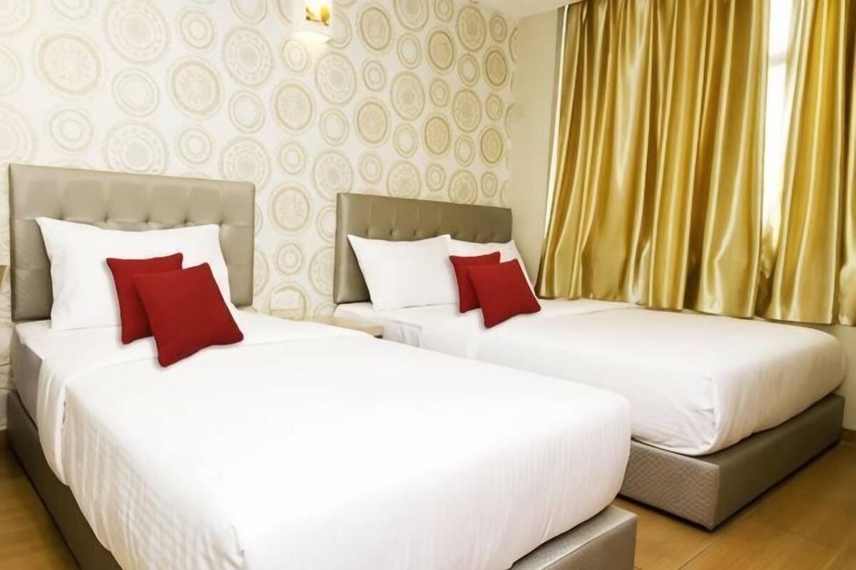 Two twin beds with headboards, white bedding, and red pillows.