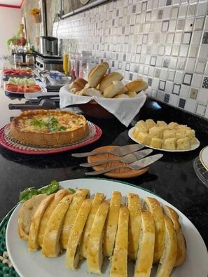 Un tavolo per buffet con diversi piatti, tra cui una quiche, panini e baguette a fette.