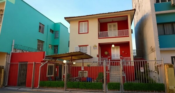 Un edificio a più piani con balconi, un ingresso con cancello e una piccola area esterna con posti a sedere.