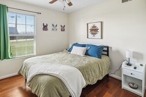 A bedroom with a bed, a nightstand, a window with blinds, and wall art. - Rainbow Ranch: Family Friendly 4 Bedroom in Lovely Williamstown, 5 min to ARK! (Williamstown)