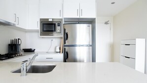 A modern kitchen with white cabinets, a stainless steel refrigerator, a microwave, and a gas stove. - Comfy 1BDR Apt 3 minutes to Train Station Burwood (Burwood)