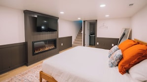 Un dormitorio con cama, chimenea, televisor y una escalera que lleva a otra habitación.