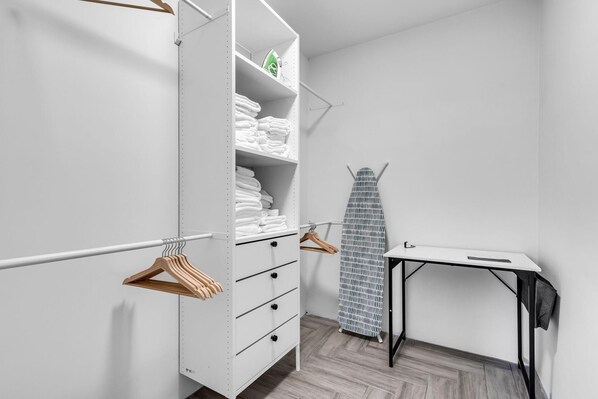 A walk-in closet with white shelving, wooden hangers, and a black ironing board. - Riverside Oasis w/ Pool & Pickleball Court (Miami)