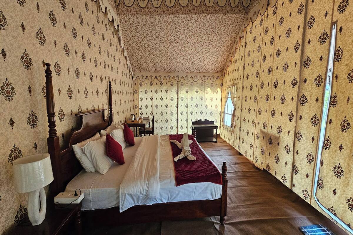 Una habitación con una cama grande, una mesita de noche, una lámpara y una ventana.