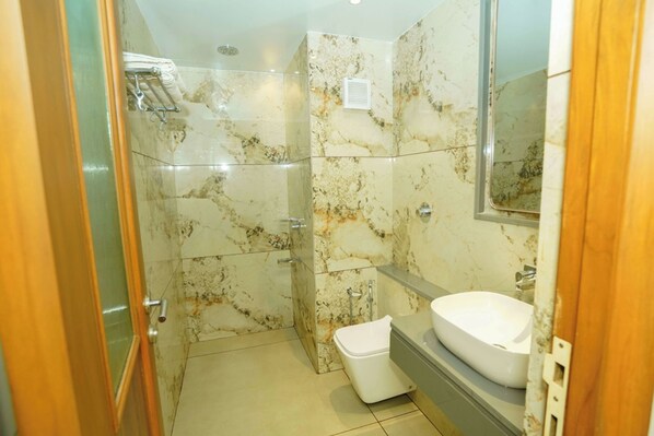Une salle de bain avec un mur en marbre, un lavabo blanc et des toilettes.