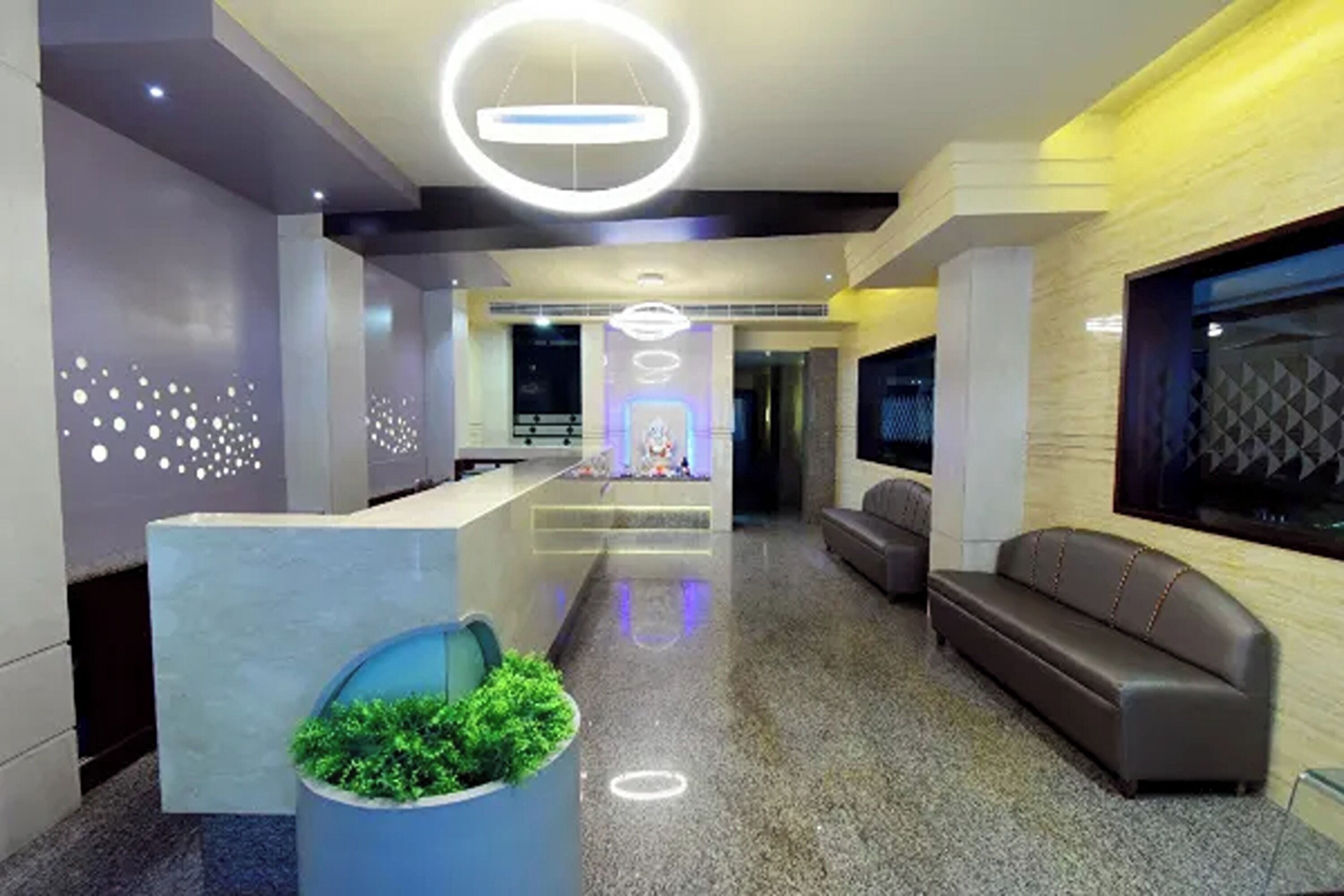 A modern lobby with a reception desk, seating area, and decorative lighting.