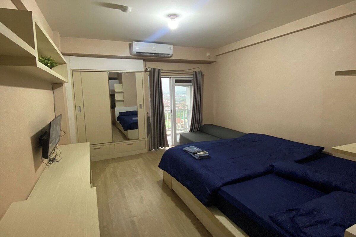 Un dormitorio con cama, televisor, armario y equipo de aire acondicionado.