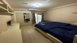 A bedroom with a bed, a TV, a wardrobe, and a window with curtains. - Jasmine Park Jp Rooms (Dramaga)