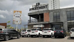 A parking lot with several cars in front of a building labeled "JP APARTMENT". - Jasmine Park Jp Rooms (Dramaga)