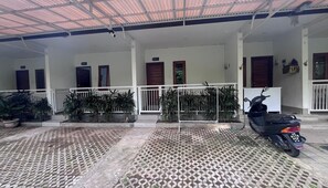 Relax in this serene outdoor space with a patterned floor, surrounded by lush greenery and a charming metal railing.