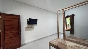 A room with a wooden door, a mounted TV on the wall, and a window with curtains. - Maisaba Living Sibang Gede (Abiansemal)