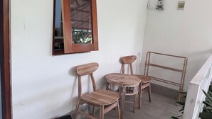 A corner of a room with two wooden chairs and a small table, a wooden-framed mirror on the wall, and a metal chair rail. - Maisaba Living Sibang Gede (Abiansemal)