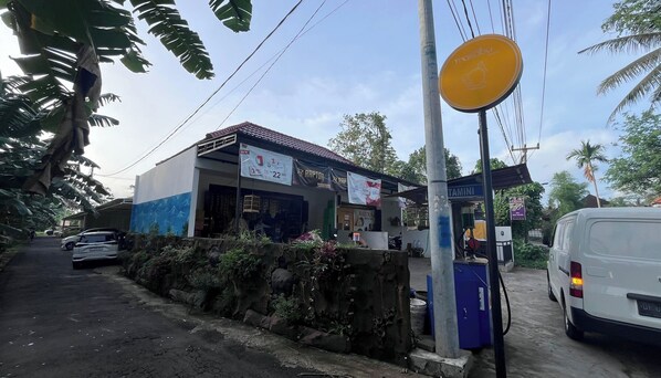 Situated along a paved road, this roadside area features a building with a service center and a signboard for a new business.
