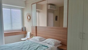 A modern bedroom with a bed, a bedside table, a chair, a mirror, and a wardrobe.