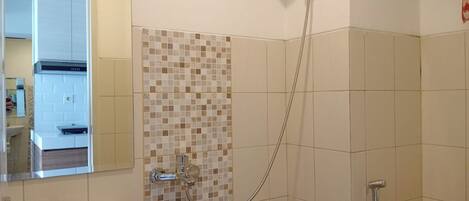Un baño con lavamanos, ducha con cabezal de ducha manual y retrete.