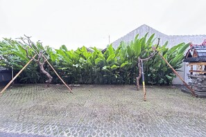 A garden area with banana plants, a stone pathway, and a traditional structure. - Sekar Tunjung Guest House Seminyak Bali (Denpasar)