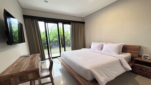 A modern bedroom with a large bed, a wooden desk, and a TV mounted on the wall. - Sekar Tunjung Guest House Seminyak Bali (Denpasar)