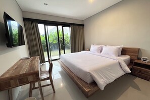Ein modernes Schlafzimmer mit einem großen Bett, einem Holztisch und einem an der Wand befestigten Fernseher.